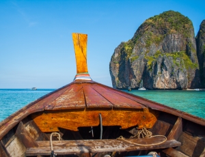 brown wooden boat showing blue sea with rock formations under clear blue sky thumbnail